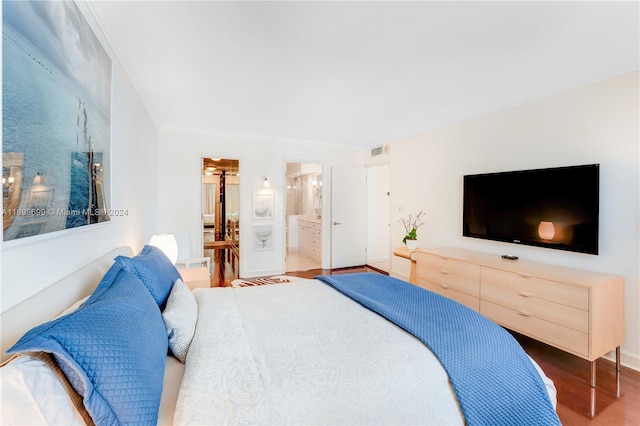 bedroom featuring hardwood / wood-style flooring, ensuite bath, and crown molding