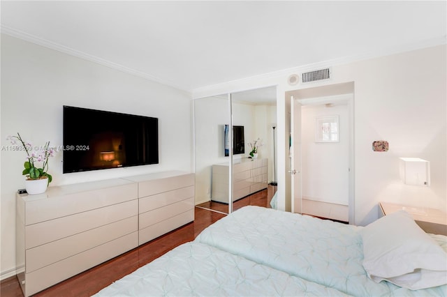 bedroom with crown molding, a closet, and dark wood-type flooring