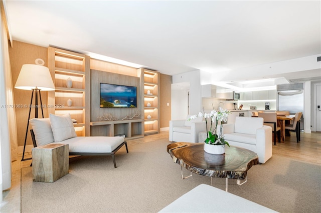 living room featuring light wood-type flooring and built in features