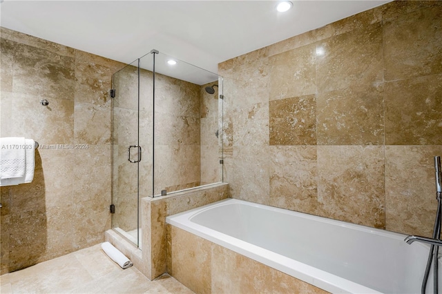 bathroom featuring plus walk in shower and tile walls