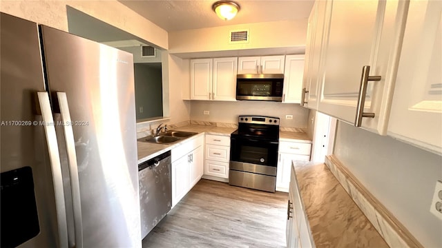 kitchen featuring white cabinetry, sink, light hardwood / wood-style floors, and appliances with stainless steel finishes