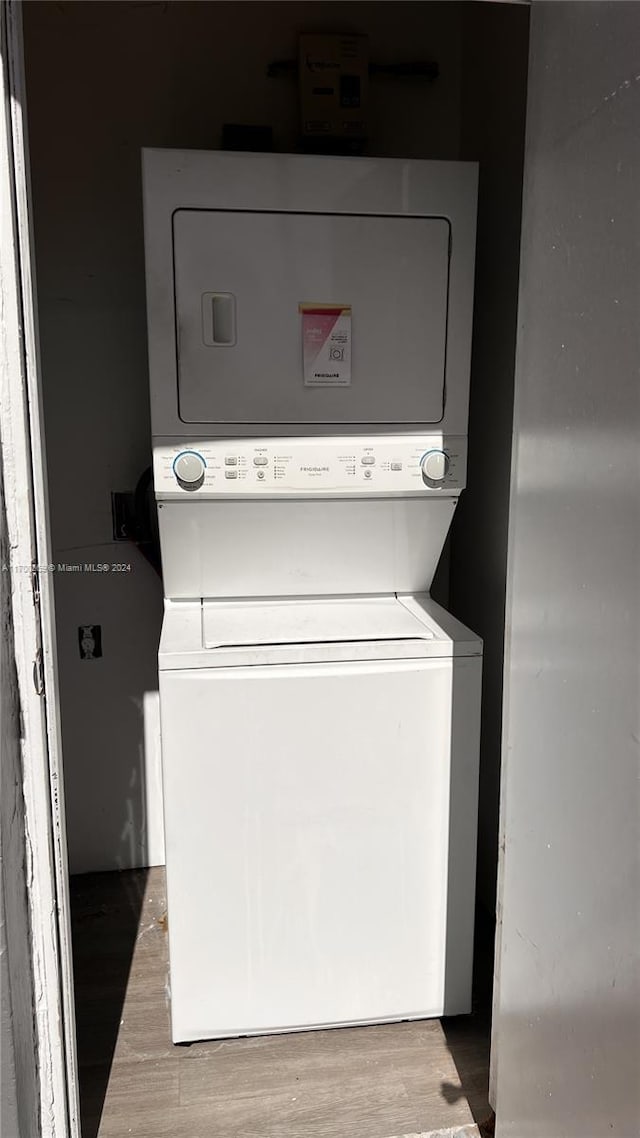 washroom with light hardwood / wood-style floors and stacked washer / drying machine