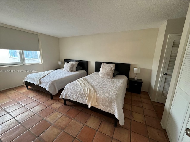 tiled bedroom featuring a closet and a textured ceiling