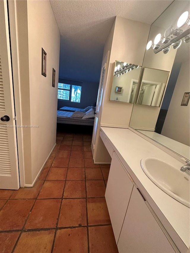 bathroom with tile patterned flooring, vanity, and a textured ceiling