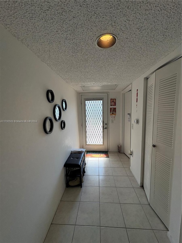 hall featuring light tile patterned floors and a textured ceiling