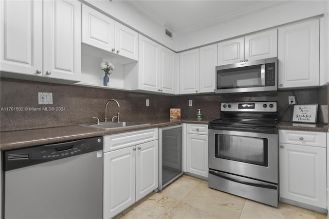 kitchen with appliances with stainless steel finishes, wine cooler, ornamental molding, sink, and white cabinetry