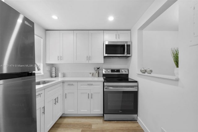 kitchen featuring white cabinets, light wood-type flooring, and appliances with stainless steel finishes