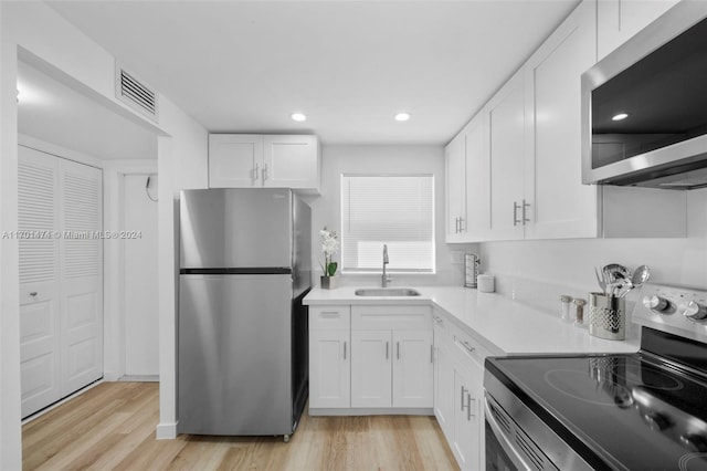 kitchen featuring white cabinets, light wood-type flooring, sink, and appliances with stainless steel finishes