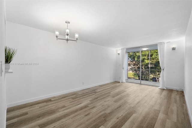 spare room featuring hardwood / wood-style floors and a notable chandelier