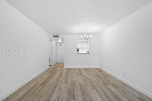 unfurnished living room with light hardwood / wood-style floors and a notable chandelier