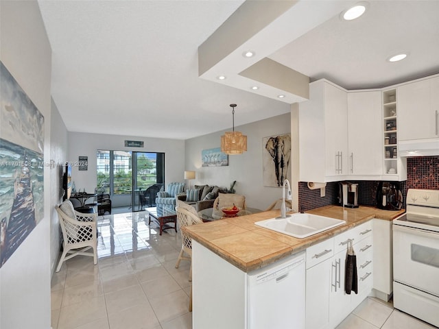 kitchen with sink, kitchen peninsula, decorative light fixtures, white appliances, and white cabinets