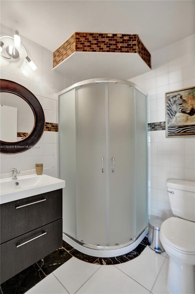 bathroom featuring tile patterned floors, vanity, a shower with door, and tile walls