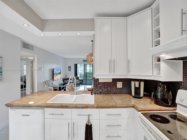 kitchen featuring tasteful backsplash, sink, white cabinets, and white appliances