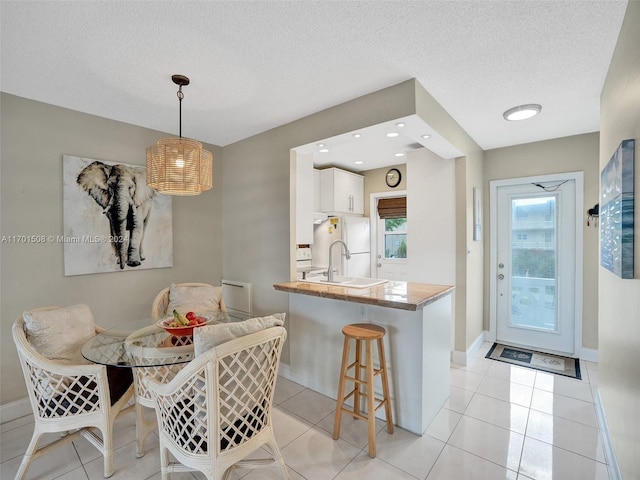 tiled dining space featuring a textured ceiling and sink