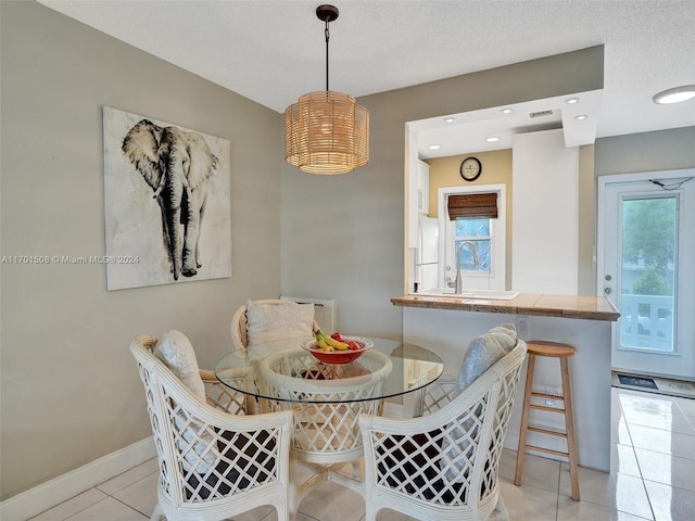 tiled dining area with sink and a textured ceiling