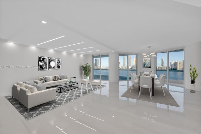 living room featuring a water view, a wealth of natural light, a notable chandelier, and a wall of windows