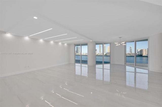 empty room with ceiling fan, a water view, a healthy amount of sunlight, and a wall of windows