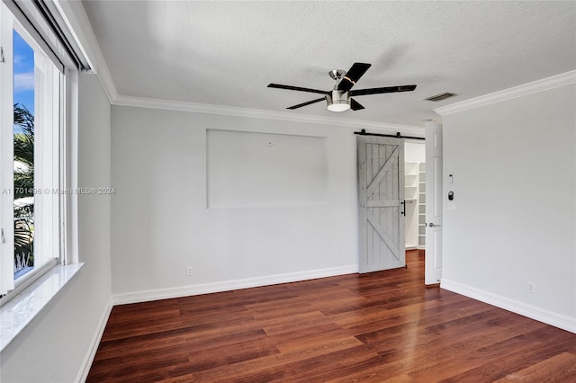 empty room featuring dark hardwood / wood-style floors, a barn door, a textured ceiling, and a wealth of natural light