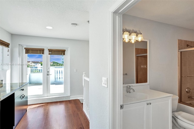 full bathroom with vanity, a textured ceiling, shower / bathing tub combination, hardwood / wood-style floors, and toilet