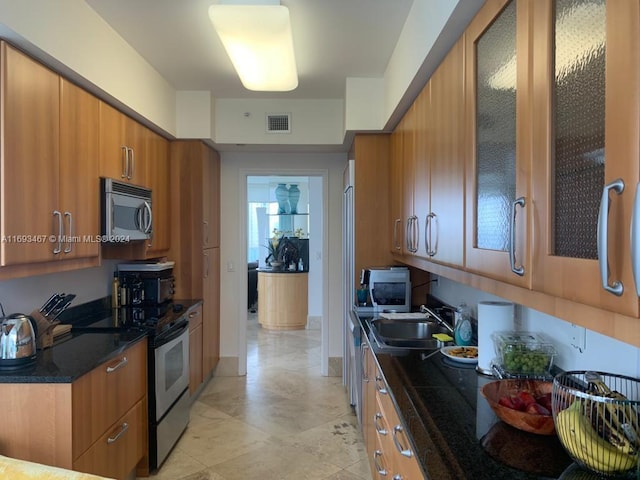 kitchen featuring sink, dark stone counters, and appliances with stainless steel finishes