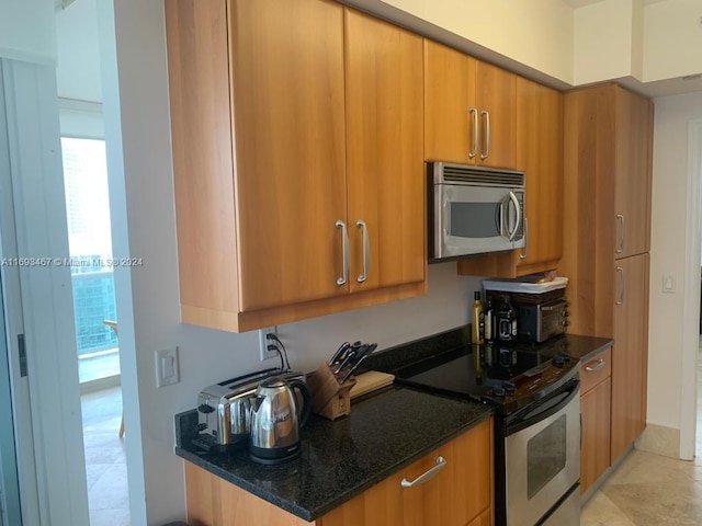 kitchen featuring electric stove and dark stone counters