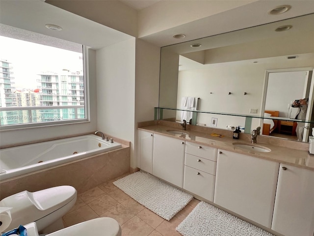 bathroom featuring tile patterned flooring, vanity, toilet, and tiled bath