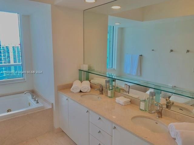 bathroom featuring tile patterned flooring, vanity, and tiled bath