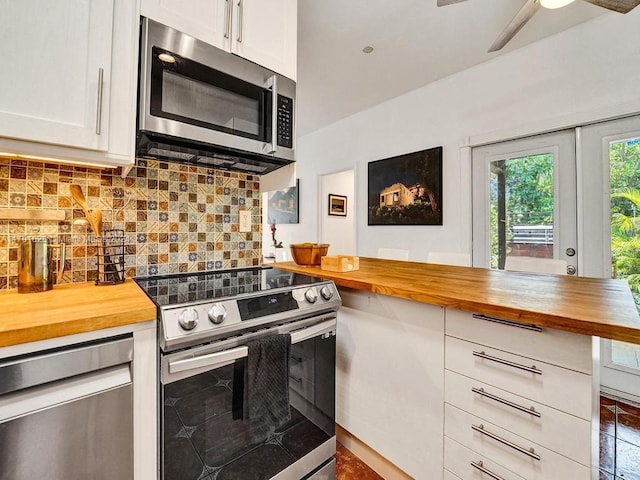 kitchen featuring appliances with stainless steel finishes, backsplash, french doors, white cabinetry, and butcher block counters