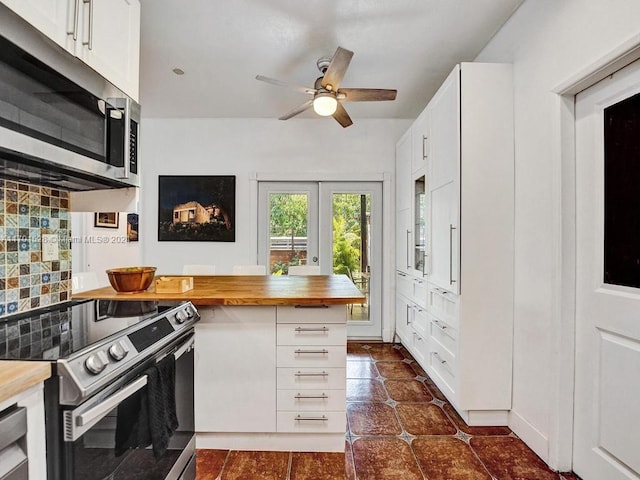 kitchen with wooden counters, stainless steel appliances, white cabinetry, and tasteful backsplash