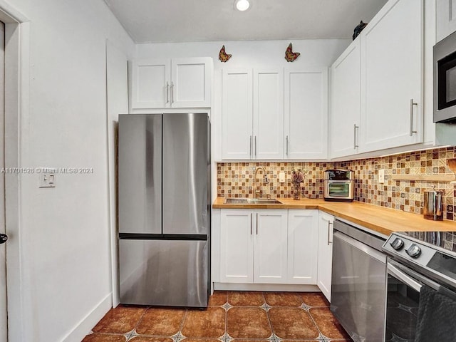 kitchen with butcher block counters, sink, white cabinets, and stainless steel appliances