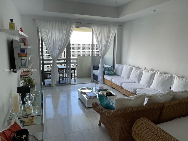 living room with light tile patterned floors and a tray ceiling