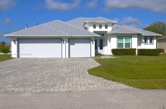 5231 NW Iredell St, Port St Lucie, FL 34986 - view of front of home featuring an attached garage, decorative driveway, metal roof, a front yard, and stucco siding