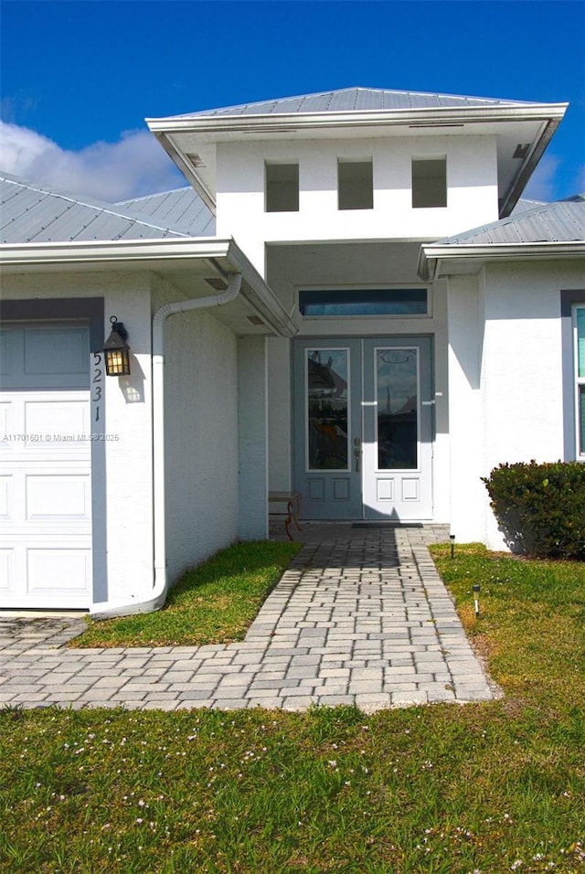 5231 NW Iredell St, Port St Lucie, FL 34986 - doorway to property featuring stucco siding, metal roof, and a garage
