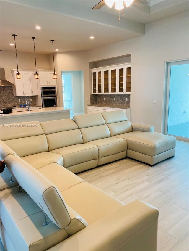 living room featuring ceiling fan, light wood-type flooring, and sink