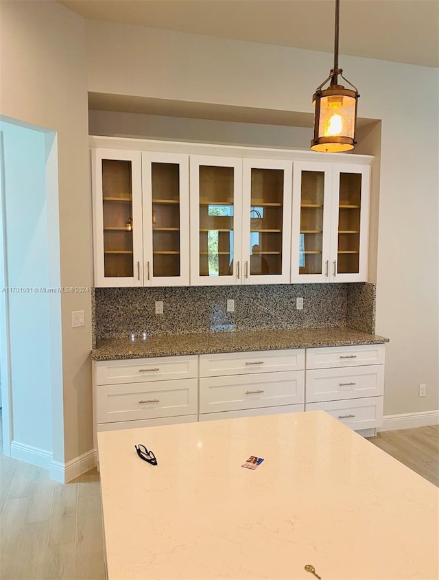 kitchen with decorative backsplash, hanging light fixtures, white cabinets, and light hardwood / wood-style floors