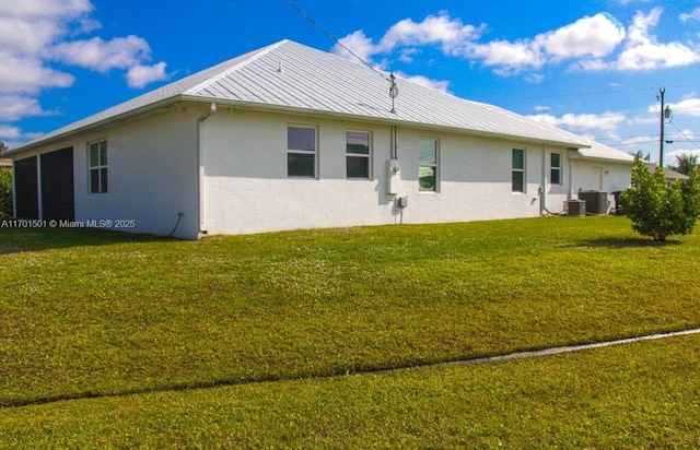 5231 NW Iredell St, Port St Lucie, FL 34986 - rear view of property featuring stucco siding, a lawn, metal roof, a standing seam roof, and cooling unit