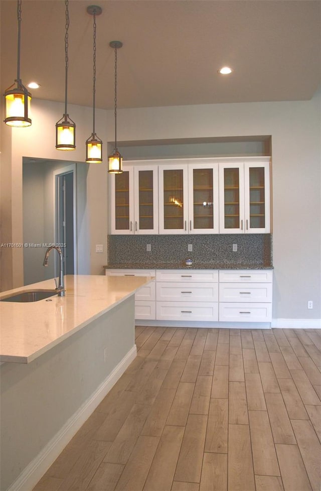 5231 NW Iredell St, Port St Lucie, FL 34986 - kitchen with a sink, backsplash, white cabinets, wood finished floors, and recessed lighting