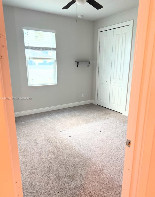 unfurnished bedroom featuring ceiling fan, a closet, and carpet