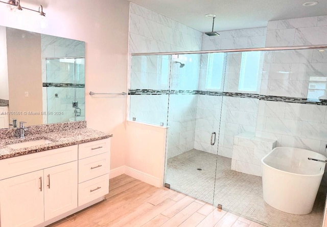 bathroom with hardwood / wood-style floors, vanity, independent shower and bath, and a healthy amount of sunlight