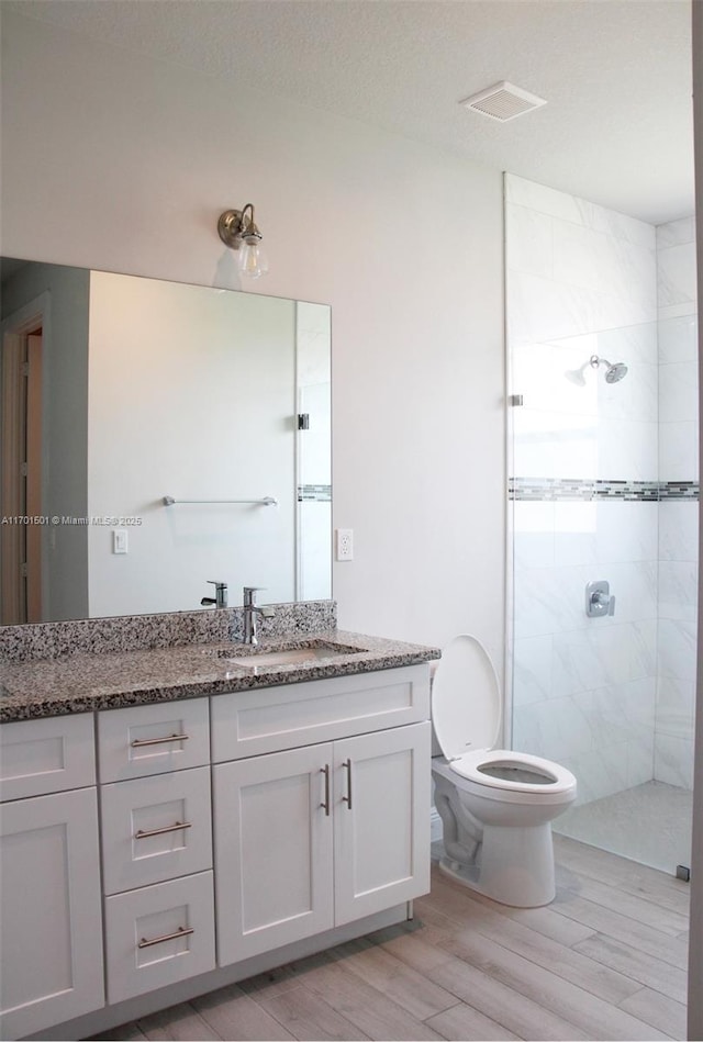5231 NW Iredell St, Port St Lucie, FL 34986 - bathroom featuring vanity, a tile shower, wood finished floors, and toilet