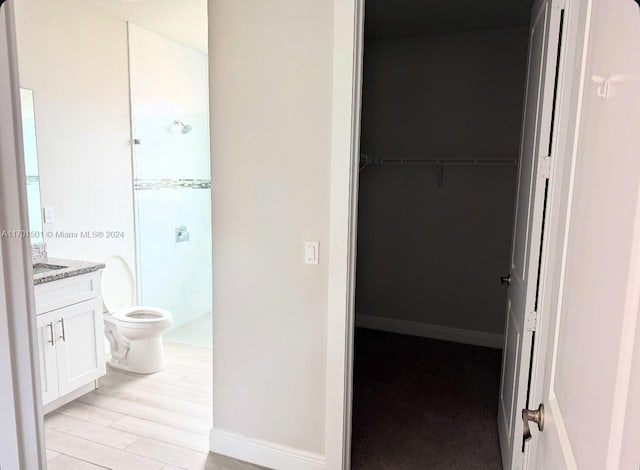 bathroom featuring hardwood / wood-style floors, vanity, toilet, and walk in shower