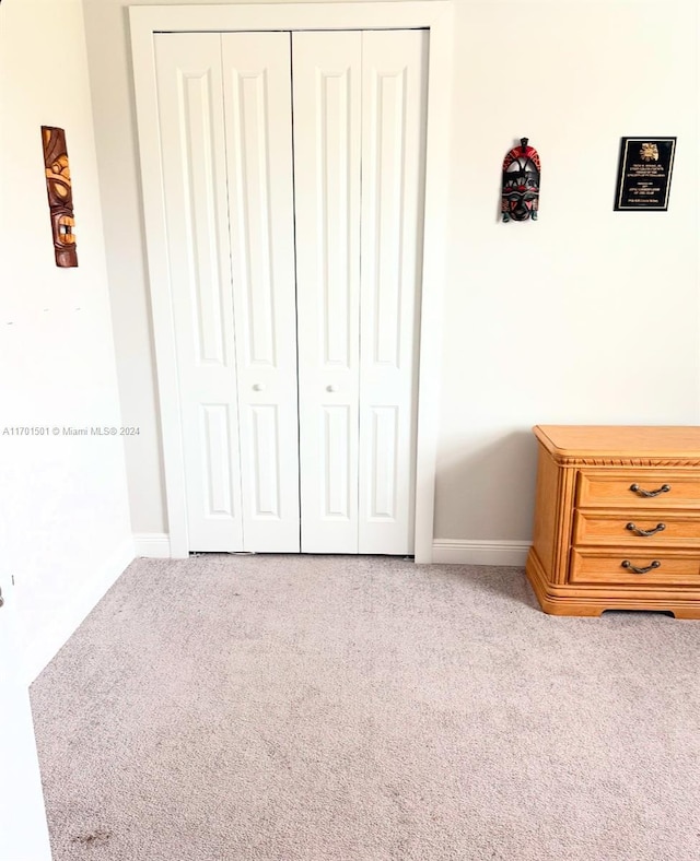 unfurnished bedroom with a closet and light colored carpet