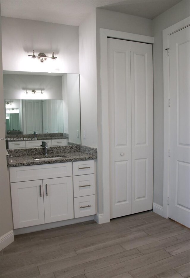5231 NW Iredell St, Port St Lucie, FL 34986 - bathroom featuring a closet, vanity, wood finished floors, and baseboards