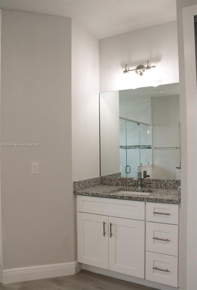 5231 NW Iredell St, Port St Lucie, FL 34986 - full bathroom with vanity, a stall shower, baseboards, and wood finished floors