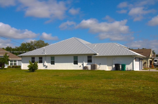 5231 NW Iredell St, Port St Lucie, FL 34986 - rear view of property with stucco siding, central air condition unit, an attached garage, a yard, and metal roof