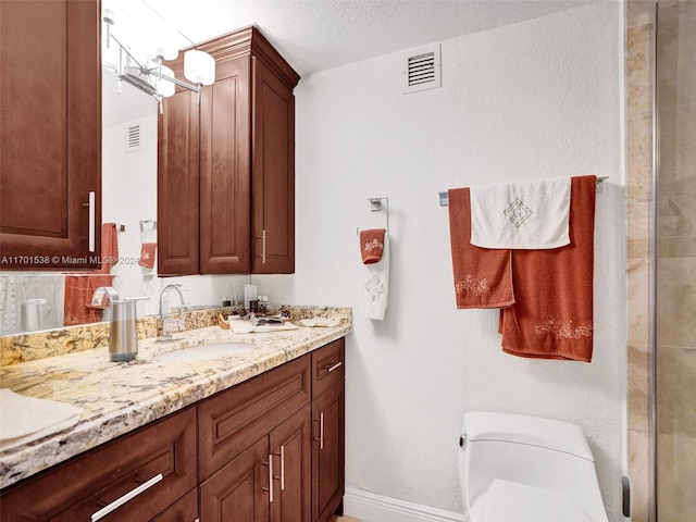 bathroom featuring vanity, a textured ceiling, and toilet