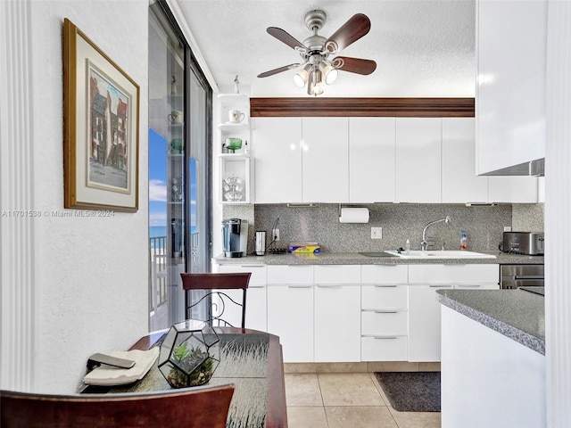 kitchen featuring tasteful backsplash, white cabinetry, sink, and a textured ceiling