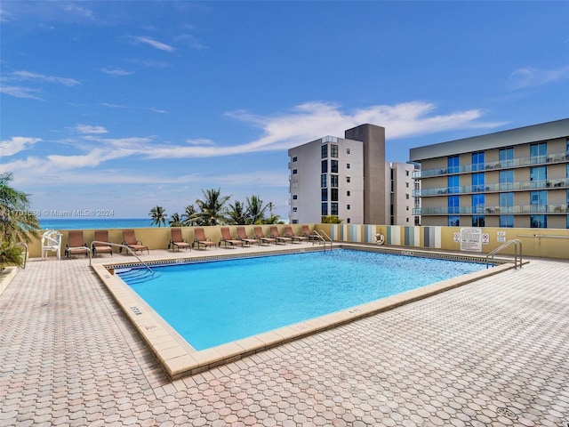 view of pool featuring a patio and a water view