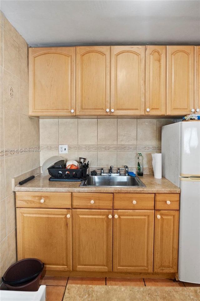 kitchen featuring tasteful backsplash, light brown cabinetry, sink, and white fridge