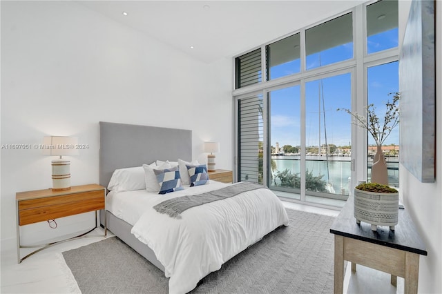 bedroom featuring access to outside, a water view, and a high ceiling